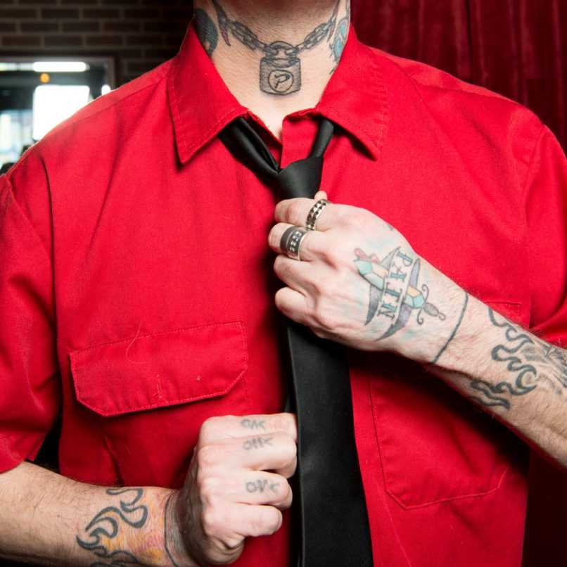 Tattooed man tieing his tie