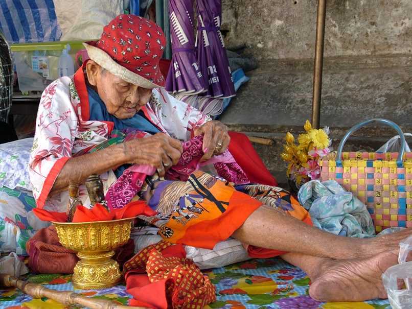 Brightly dressed elderly woman in market in Thailand