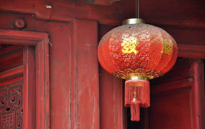 Asian lantern decoration hanging next to red temple