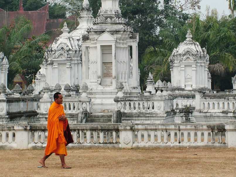 Monk walking in front of ancient temple structure in Thailand