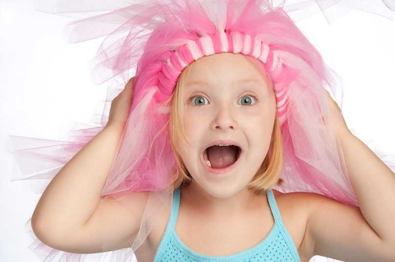 Little girl smiling in front of white background with tutu on her head